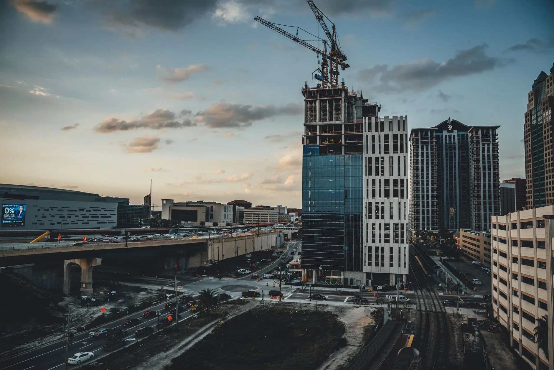 Edifício em construção com guindaste ao entardecer em área urbana